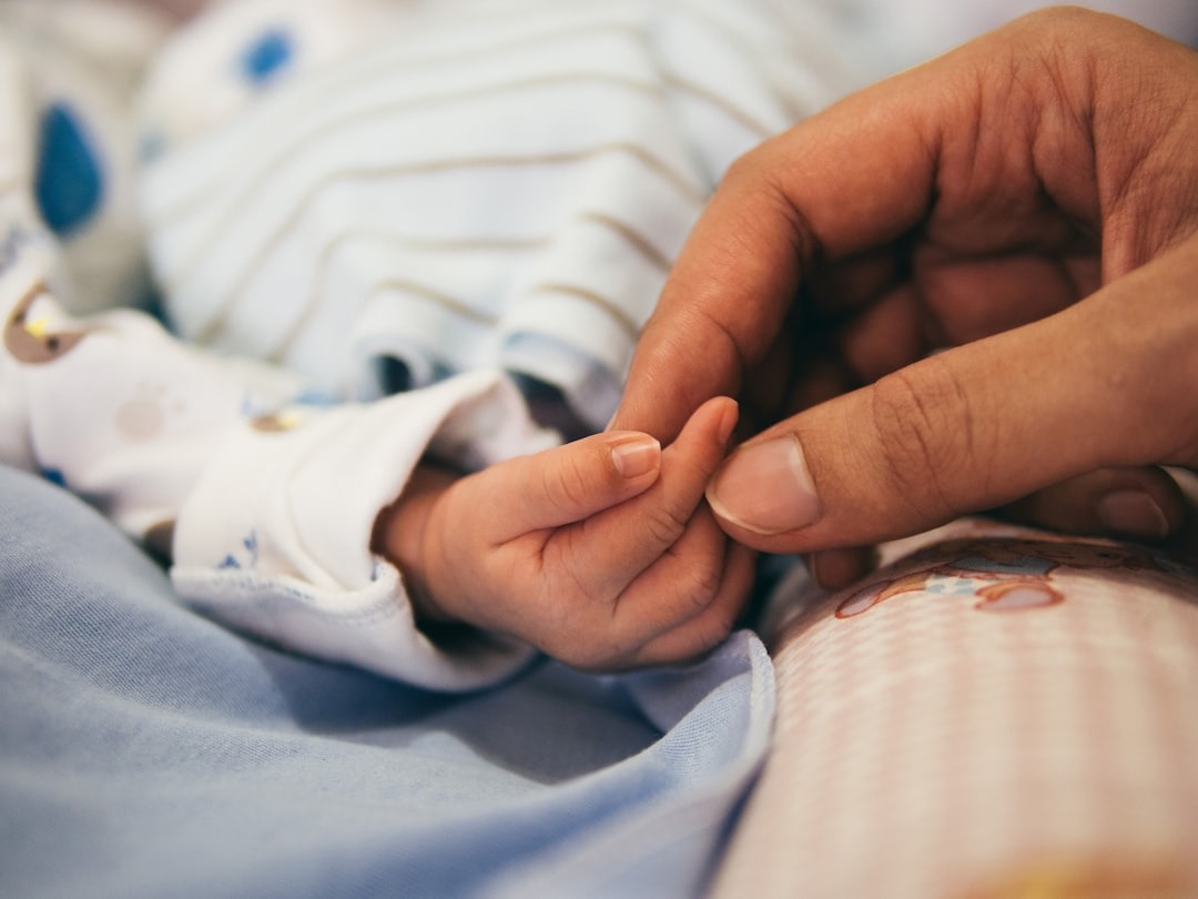 La mano di un adulto che tiene la manina di un neonato