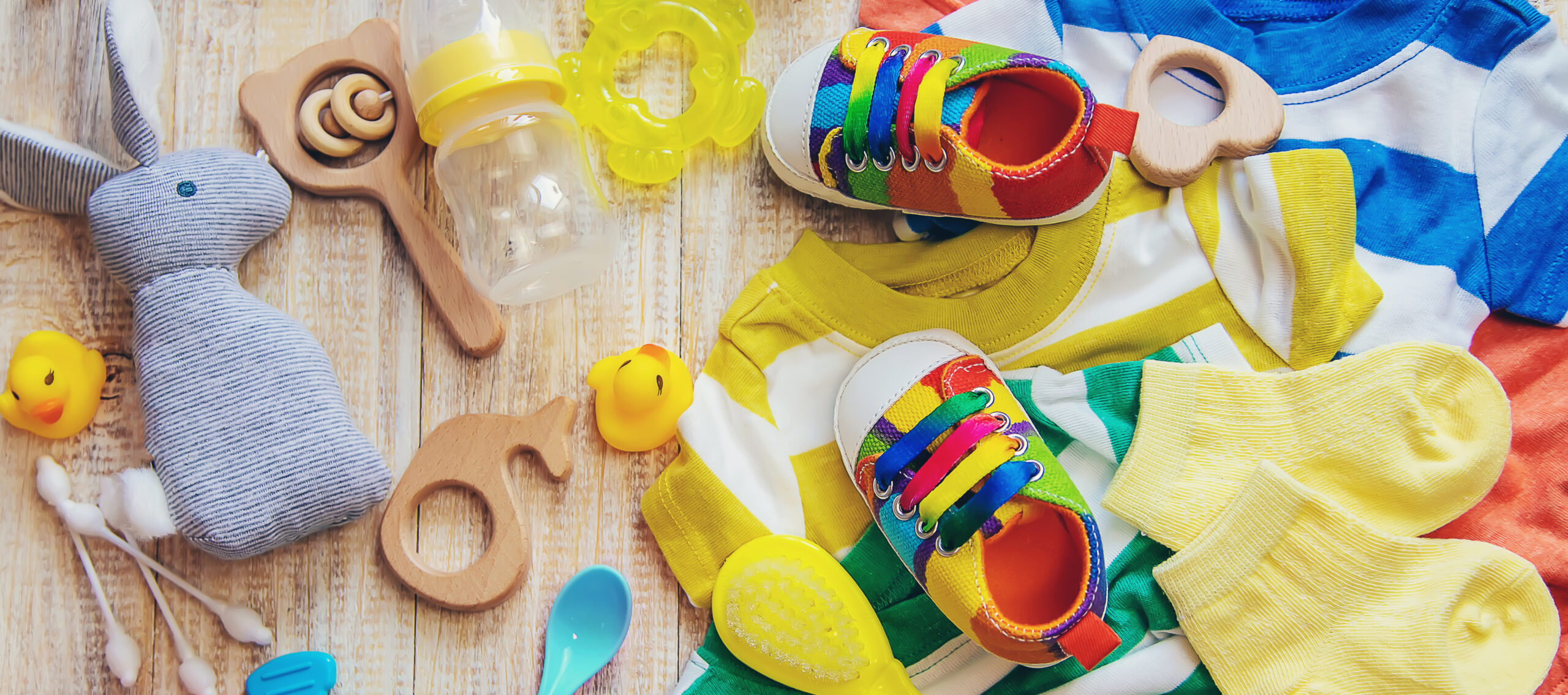 Oggetti per l'infanzia tra cui peluche, sonaglio, biberon, scarpette e vestiti neonatali