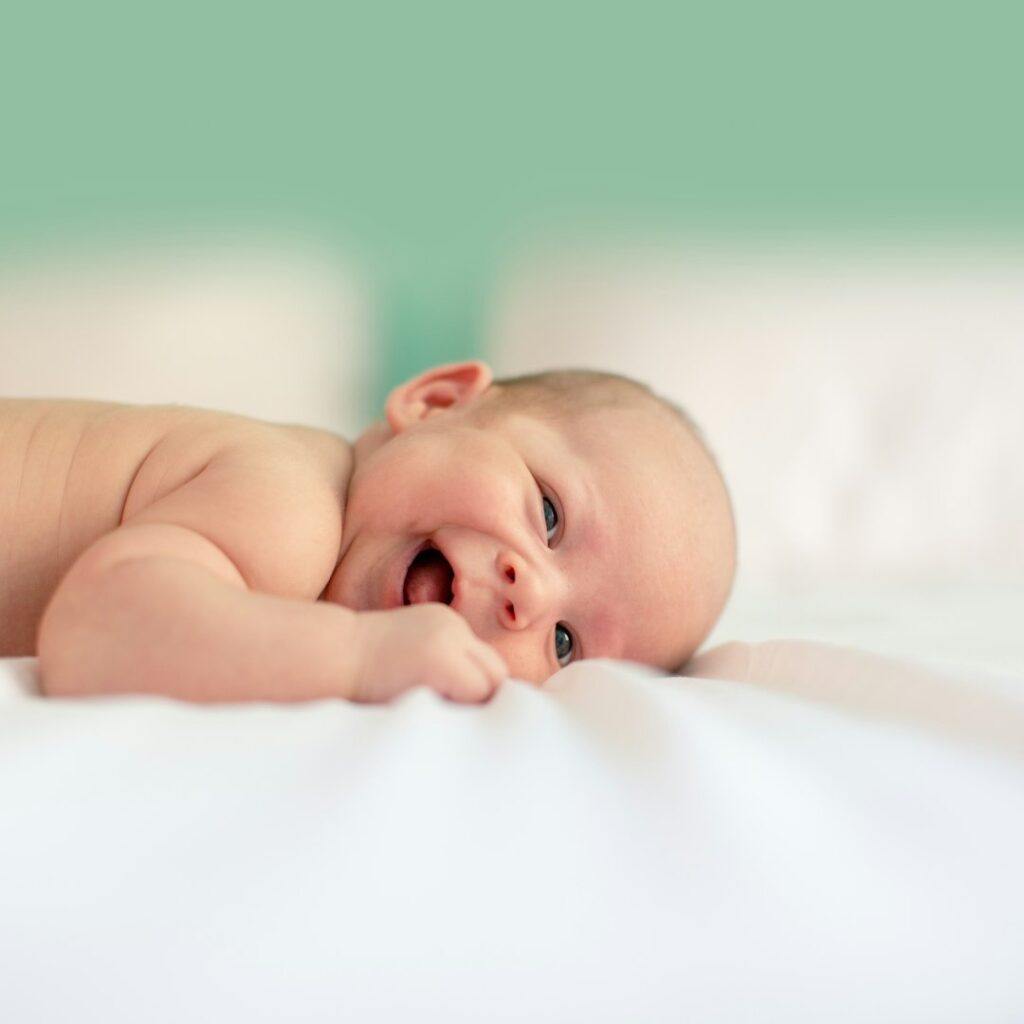 Neonato sdraiato sul pancino che ride