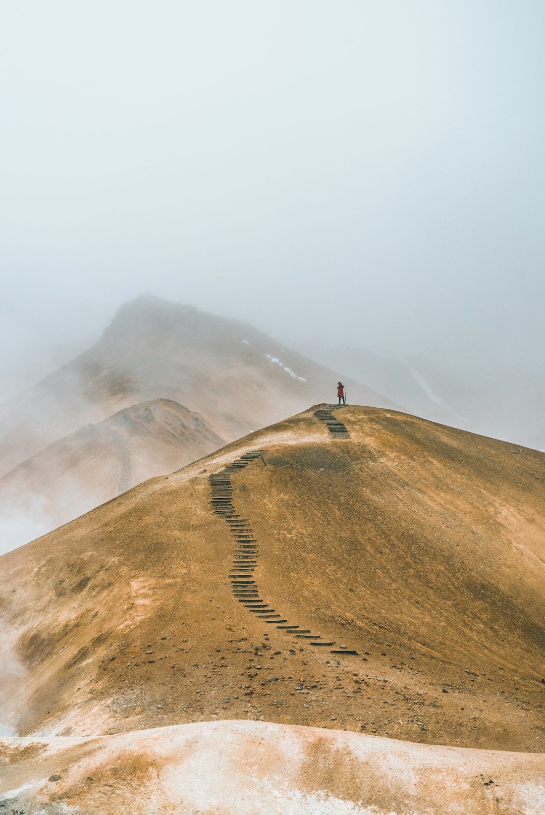 Persona sulla cima di un colle con sfondo di nebbia